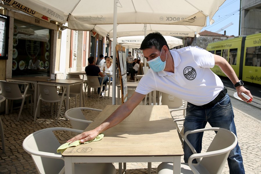A waiter cleans tables at restaurant terrace in Lisbon, Portugal, April 5, 2021. (Photo by Pedro Fiuza/Xinhua)